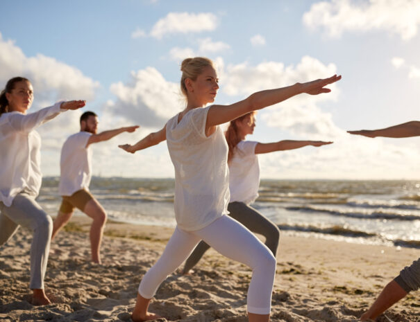 group-of-people-making-yoga-exercises-on-beach-2023-11-27-05-16-22-utc-scaled.jpg